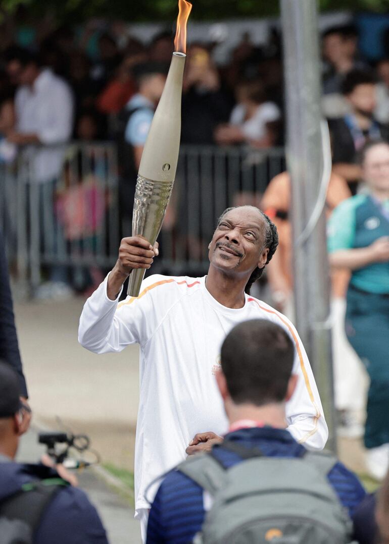 El rapero estadounidense Snoop Dogg sostiene la antorcha como parte del relevo de la antorcha de los Juegos Olímpicos de París 2024, el día de la ceremonia de apertura, en Saint-Denis, en las afueras de París, el 26 de julio de 2024.