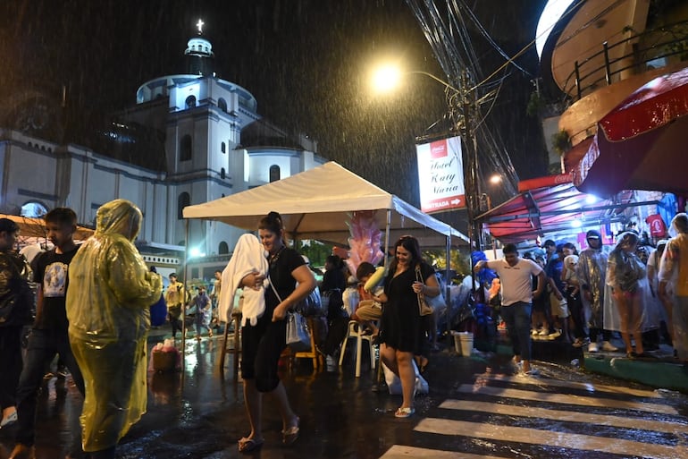 La gente trata de cubrirse de la lluvia como sea en Caacupé.