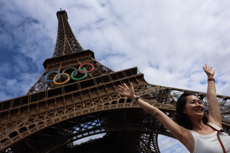 Una turista se fotografía junto a la Torre Eiffel que luce los aros olímpicos con motivo de la celebración de los Juegos.