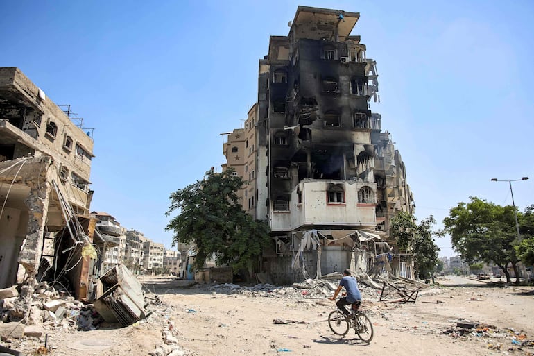 Un hombre en bicicleta pasa junto a un edificio destruido en la Ciudad de Gaza, el lunes.
