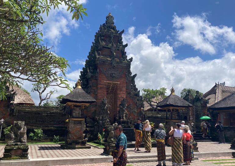 Turistas visitan un templo en Bali. El sarong (falda larga para hombres y mujeres) suele ser obligatorio.