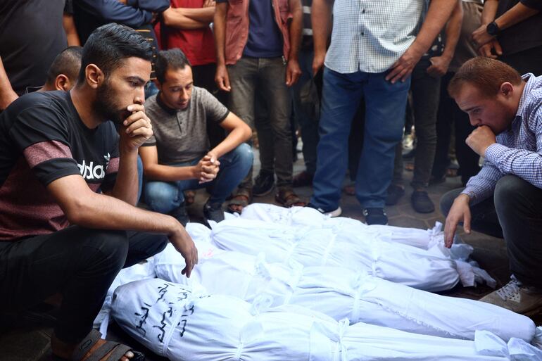 Varias personas observan los cuerpos de víctimas de un bombardeo israelí a una escuela que albergaba a personas desplazadas en Deir el-Balah, este lunes.