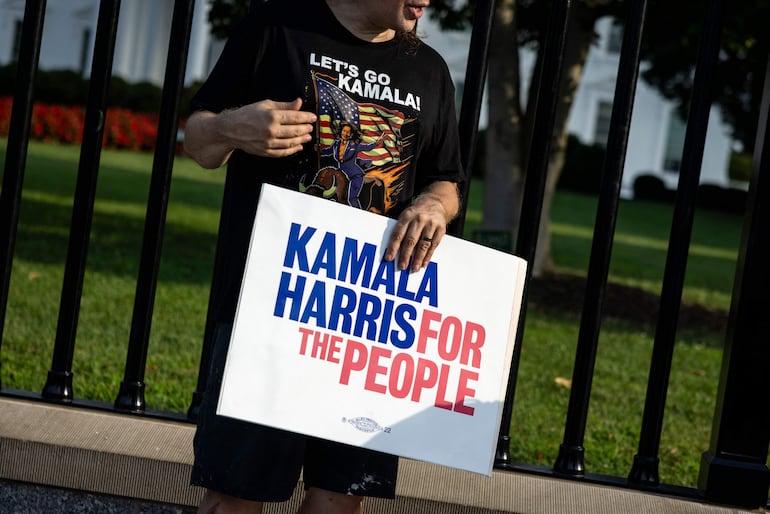 Un hombre con una camiseta que dice "Lets Go Kamala" sostiene un cartel de apoyo a la vicepresidenta estadounidense Kamala Harris a lo largo de la avenida Pennsylvania frente a la Casa Blanca en Washington, DC.