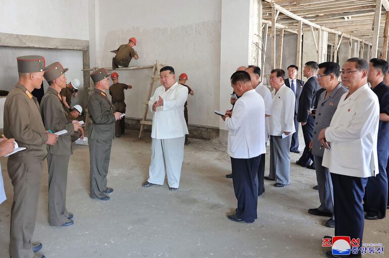 El líder norcoreano Kim Jong Un (centro, de blanco) con dirigentes e ingenieros de la industria militar. (KCNA/AFP)