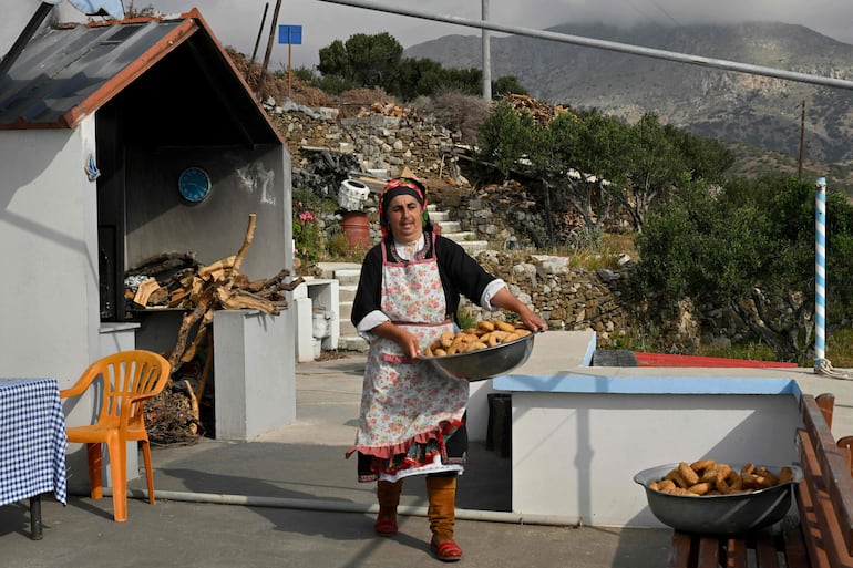 La panadera Irini Chatzipapa lleva bizcochos recién horneados en su taller de hornos en el pueblo de Diafani en la isla de Cárpatos.