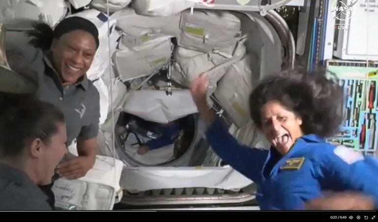 La astronauta Suni Williams (d) es recibida por su colega Butch Wilmore (C) a bordo de la Estación Espacial International.