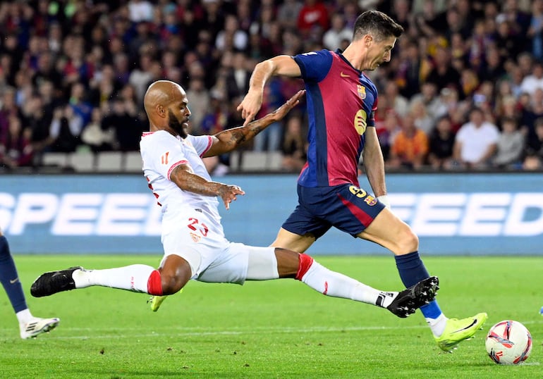 TOPSHOT - Sevilla's Brazilian defender #23 Marcao Teixeira (L) tackles Barcelona's Polish forward #09 Robert Lewandowski during the Spanish league football match between FC Barcelona and Sevilla FC at the Estadi Olimpic Lluis Companys in Barcelona on October 20, 2024. (Photo by Josep LAGO / AFP)