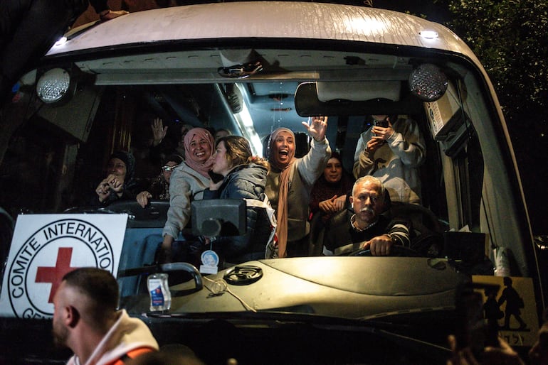 Los prisioneros palestinos liberados saludan a la multitud desde un autobús de la Cruz Roja que los sacó de la prisión militar israelí de Ofer, en Cisjordania ocupada, a su llegada a Beitunia, en las afueras de Ramallah, en la madrugada del 20 de enero de 2025. 