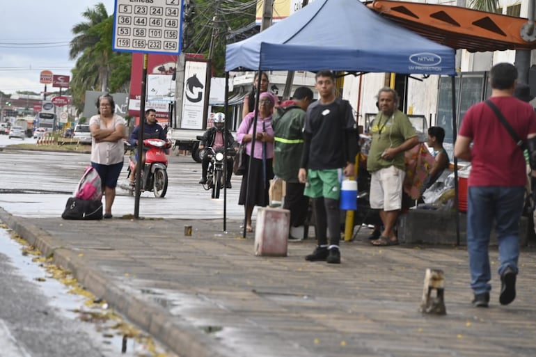 Pasajeros esperan colectivos en las paradas, mientras los empresarios del transporte regulan el flujo de vehículos y los someten a condiciones indignas.