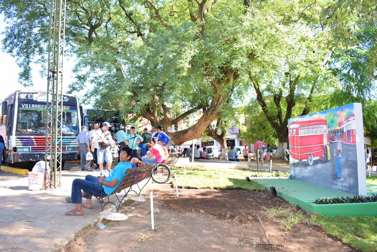 La gente resguardándose del sol en la parada de ómnibus de Villarrica. 