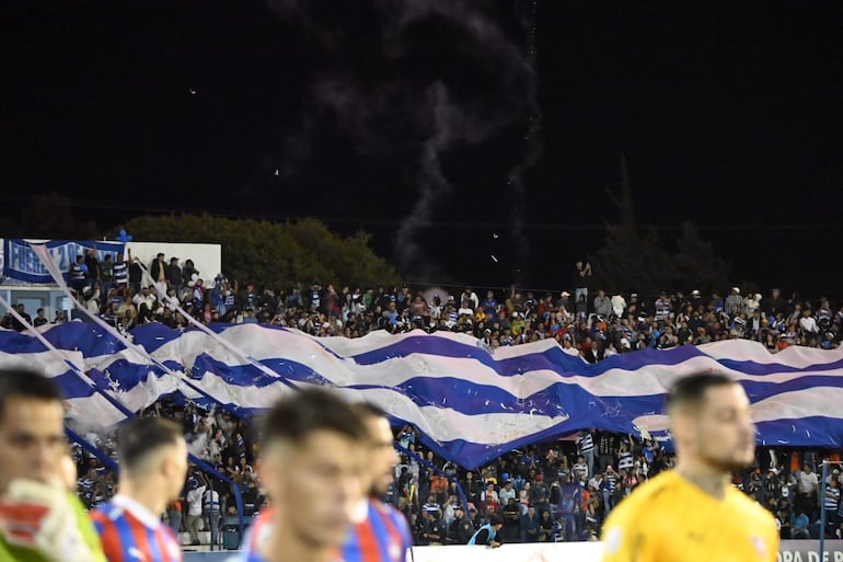 Los hinchas de 2 de Mayo extienden una bandera para recibir al equipo en el partido frente a Cerro Porteño en el Río Parapití.