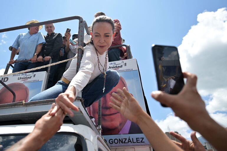 La líder de la oposición venezolana María Corina Machado (C) se estira para saludar a sus partidarios durante una protesta convocada por la oposición para que se reconozca la "victoria" electoral.