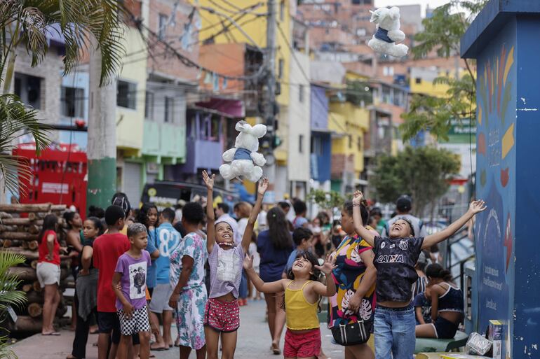 Niños reciben los regalos patrocinado de unos grandes almacenes para celebrar una navidad, en Paraisopolis, la segunda mayor favela de Sao Paulo (Brasil). En las bulliciosas y laberínticas calles de Paraisópolis, los habitantes de la segunda mayor favela de São Paulo se preparan para celebrar una Navidad diferente, marcada por las carencias económicas.