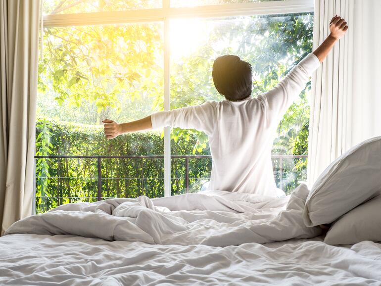 Un hombre se despereza en su cama al amanecer.