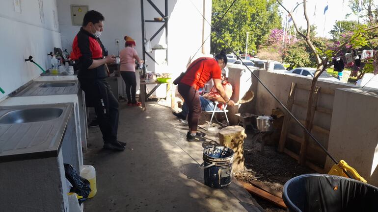 Varias personas trabajan en la cocción de alimentos de la olla popular en el albergue del IPS Central.