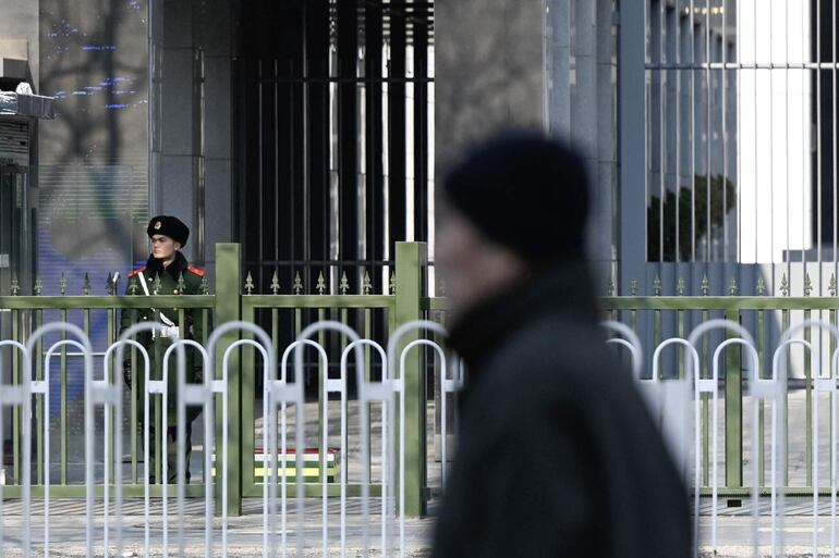 Un oficial de policía paramilitar chino (izq.) hace guardia frente a la embajada de Australia en Beijing el 5 de febrero de 2024. El gobierno de Australia dijo el 5 de febrero que el escritor Yang Jun había recibido una sentencia de muerte suspendida en China, describiéndola como una "noticia desgarradora".