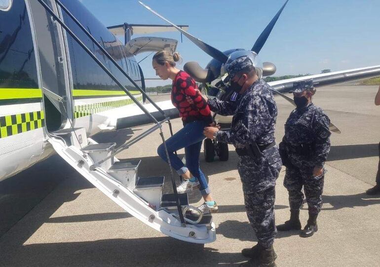 Policías salvadoreños suben a Margareth Chacón al avión que la llevó a Colombia tras su captura.