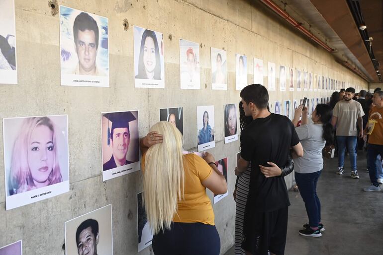 Familiares y vecinos del barrio Trinidad recuerdan a sus seres queridos en el mural con fotografías de los sobrevivientes, ubicado en el memorial 1A.