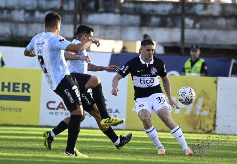 Facundo Zabala levanta el balón al área con la marca de Ángel Martínez y Aquilino Giménez