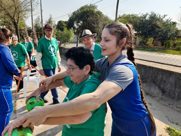 Una estudiante de educación física de la Universidad Nacional de Pilar (UNP) enseña a una persona adulta como realizar los ejercicios físicos para fortalecer la salud.