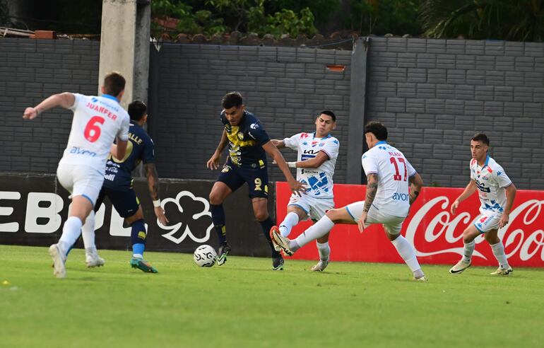 El delantero de Trinidense, Óscar Giménez intenta sacarse la marca de los jugadores de Nacional para ensayar un remate al arco.