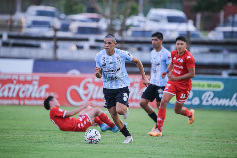 Patricio Coronel escapa en velocidad luego de recuperar el balón de los pies del defensor de Nacional Carlos Espínola, quien se encuentra en el suelo.