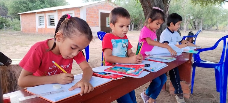 Los bancos de la pequeña capilla, calzados con ladrillos, también sirven de mesa a estos alumnos en el Chaco.