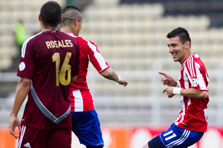 El jugador paraguayo Héctor Bénitez (d) celebra con su compañero de equipo Víctor Ayala (c) una anotación ante Venezuela el viernes 11 de octubre de 2013, durante un partido disputado entre Venezuela y Paraguay por la fase clasificatoria suramericana al Mundial Brasil 2014, en San Cristóbal (Venezuela).