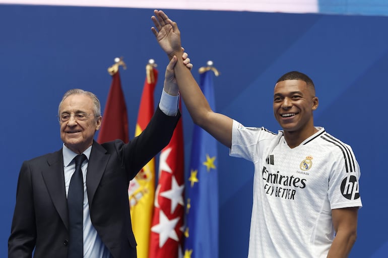 El jugador francés Kylian Mbappé (d) y el presidente Florentino Pérez en la presentación como jugador del Real Madrid en el estadio Santiago Bernabéu, en Madrid, España. 
