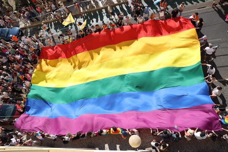 Un grupo de personas sostiene una gran bandera con los colores del arcoiris mientras participan en el 24º Desfile del Orgullo de Lisboa, en Lisboa, Portugal.
