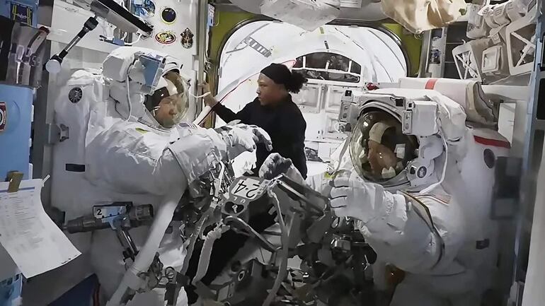 Fotografía cedida por NASA TV de una captura de video donde aparece la astronauta Jeanette Epps (centro) mientras ayuda a sus colegas Mike Barratt (izquierda) y Tracy C. Dyson (derecha) dentro de la esclusa de aire Quest. La caminata espacial de los astronautas de la NASA Tracy C. Dyson y Mike Barrat, prevista para este lunes en la Estación Espacial Internacional (EEI), fue suspendida debido a "una fuga de agua en la unidad de servicio y enfriamiento del traje espacial" de la primera, informó la agencia estadounidense.