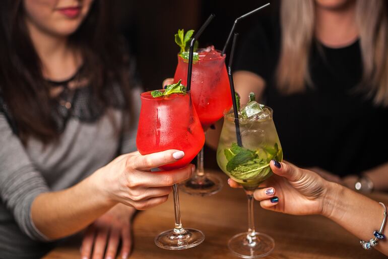 Tres mujeres brindan con tragos alcohólicos.