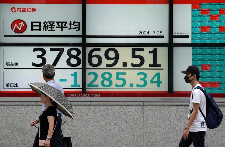 Los peatones pasan junto a una exhibición que muestra la información de cierre del promedio bursátil Nikkei de Tokio en Tokio, Japón.