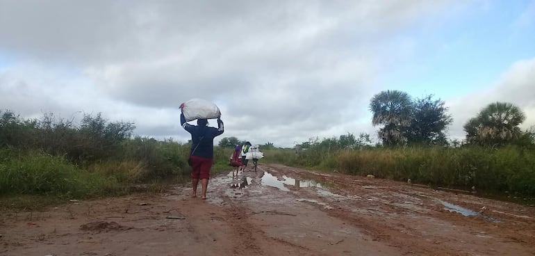 Mujeres indígenas acarrean alimentos en un camino intransitable del Chaco.