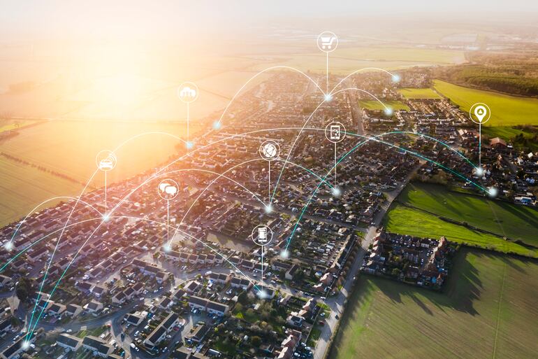 Una ciudad inteligente de varias manzanas conectadas entre sí por redes virtuales y rodeada de parcelas verdes.