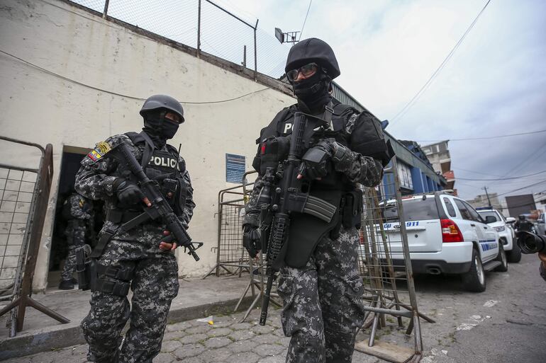 Integrantes de la policía nacional de Ecuador esperan, frente a la cárcel de El Inca, en Quito (Ecuador). Las bandas narcos se enfrentan en plena vía pública.  (EFE)