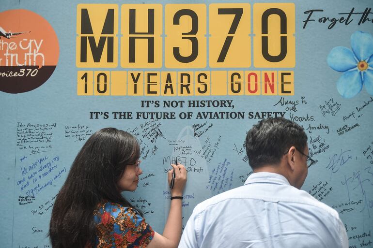 Una mujer escribe un mensaje en un mural en conmemoración del décimo aniversario de la desaparición del vuelo MH370, el pasado domingo en Pekín, China.