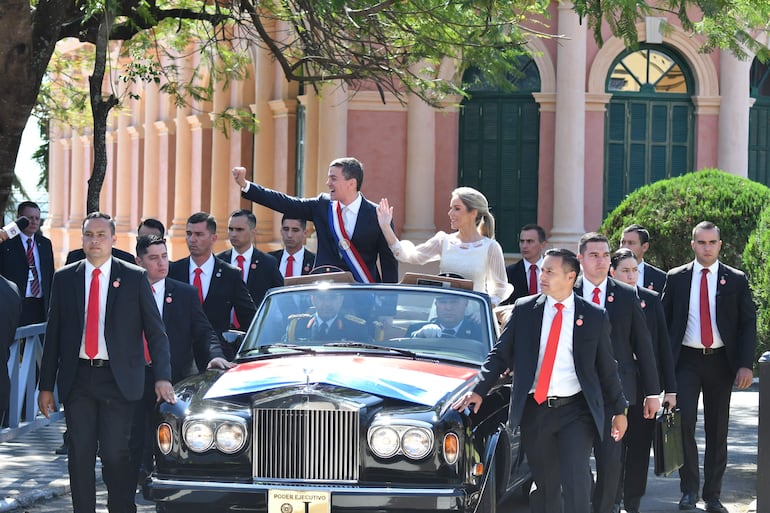 El nuevo presidente de Paraguay, Santiago Peña, y la primera dama, Leticia Ocampos, saludan durante un recorrido en coche a simpatizantes tras la ceremonia de investidura hoy, en Asunción.