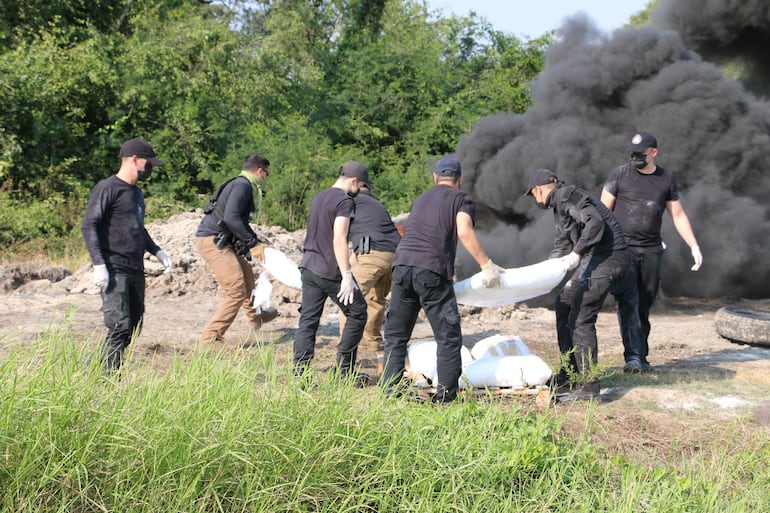 Agentes especiales de la Senad arrojan al fuego las bolsas con cocaína, que generan humo negro.