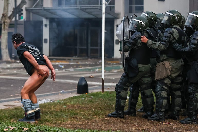  Un hombre se desnuda frente a la policía durante enfrentamientos entre la policía y personas que protestan a las afueras del senado durante un debate este miércoles, en Buenos Aires (Argentina)