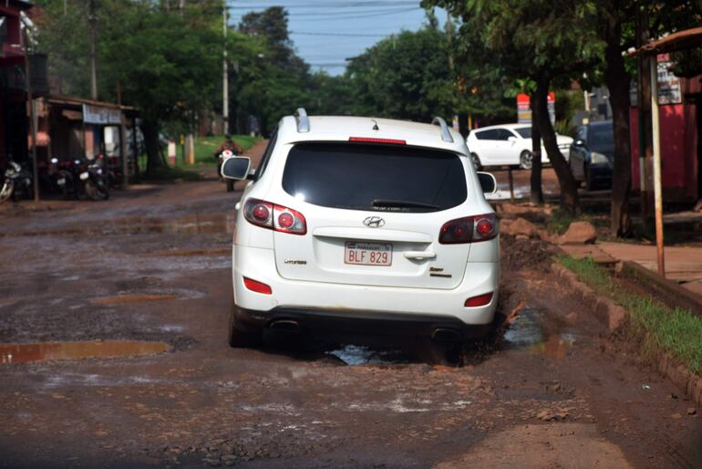 Un vehículo cruza por una zona minada de baches de la calle céntrica con riesgo de romper el tren delantero.