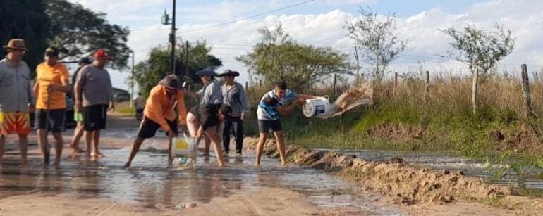 Pobladores de Laguna Itá desaguan con baldes y palas el camino vecinal que conecta la ruta principal con el distrito de San Juan de Ñeembucú.