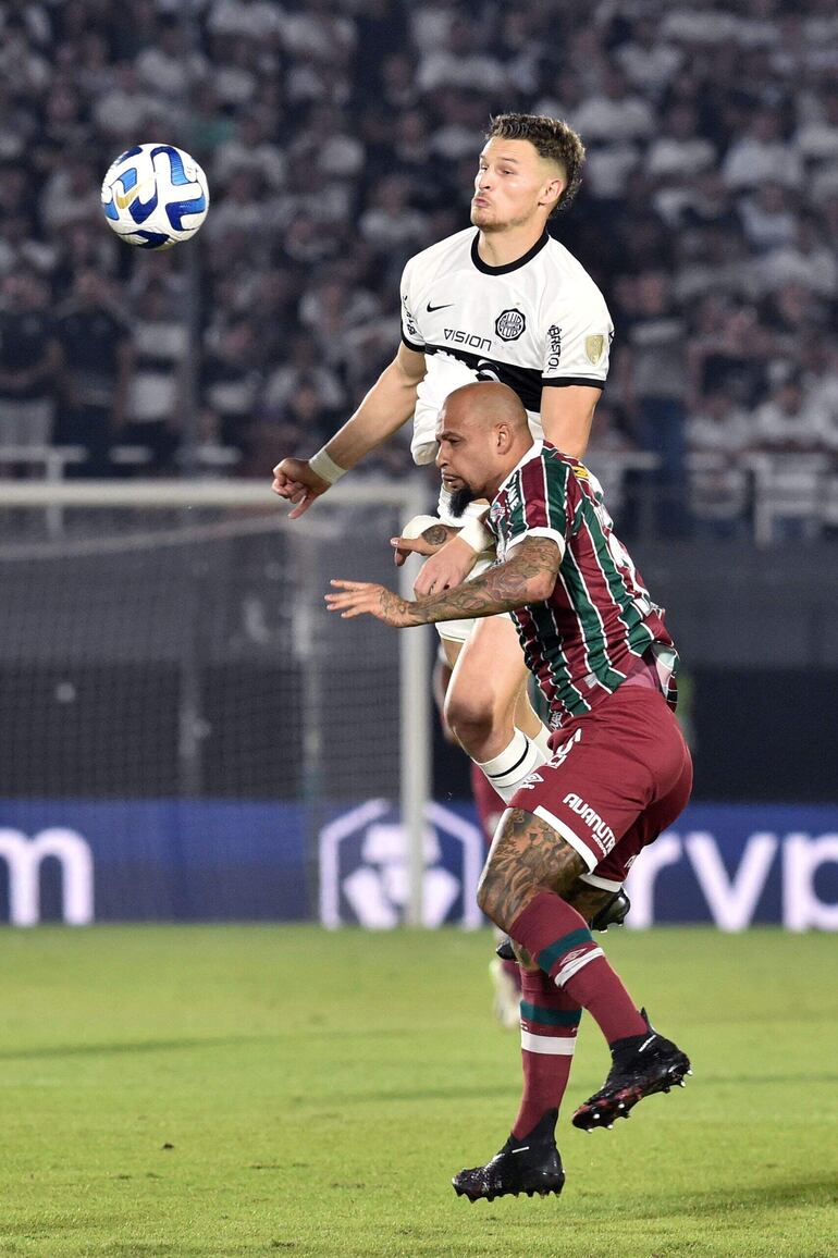 El delantero argentino del Olimpia, Facundo Bruera (i), y el mediocampista del Fluminense, Felipe Melo, saltan al balón durante el partido de vuelta de los cuartos de final de la Copa Libertadores entre el Olimpia de Paraguay y el Fluminense de Brasil en el estadio Defensores del Chaco de Asunción, el 31 de agosto de 2023.