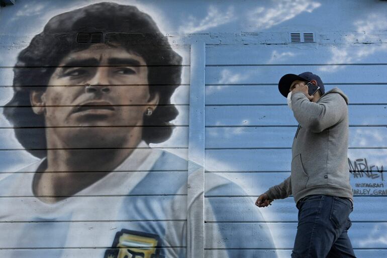 Una persona pasa junto a un mural pintado por el artista Marley afuera del estadio Diego Armando Maradona mientras la gente se reúne para conmemorar el segundo gol de la leyenda argentina contra Inglaterra durante la Copa Mundial de la FIFA México 1986 en su 35° aniversario, en Buenos Aires.