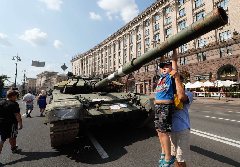 Un niño juega a colgarse del cañón de un tanque militar ruso, capturado por Ucrania, en las calles de Kiev.