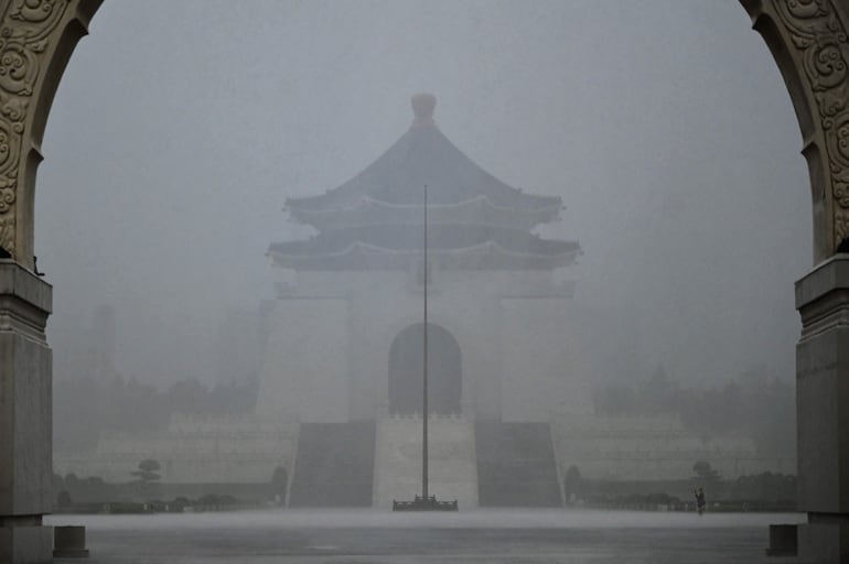 Un visitante (abajo a la derecha) toma fotografías frente al Salón Conmemorativo de Chiang Kai-shek bajo una fuerte lluvia debido a los patrones climáticos causados ​​por el tifón Gaemi en Taipei.