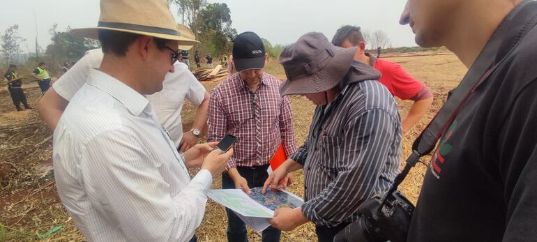 El perito de la fiscalía, Ing Víctor Ibarra, y el topógrafo, Celso Salinas, observan unos planos satelitales con la ubicación del inmueble invadido.