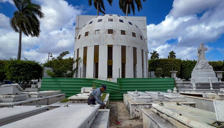 Un empleado del Cementerio de Colón limpia entre las tumbas cerca del mausoleo de Catalina Lasa y Juan Pedro Baro (C) en La Habana.