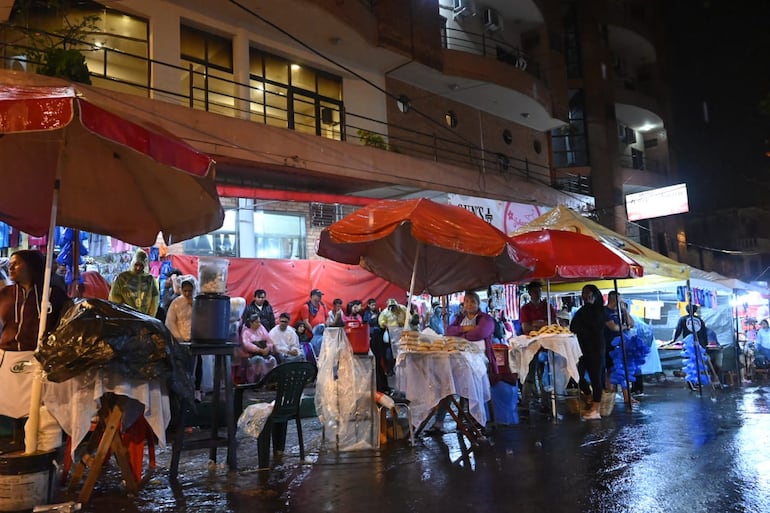 Vendedoras de chipa tratan de proteger sus productos debido a la lluvia.