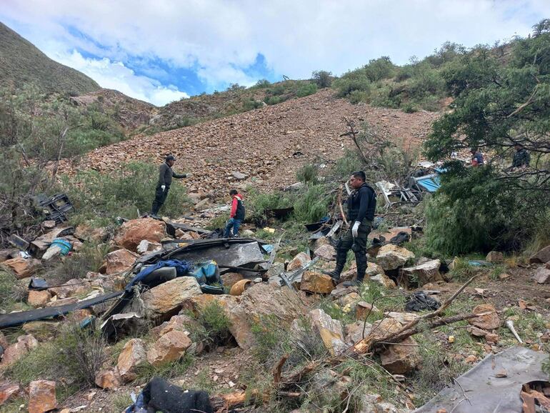 Esta fotografía publicada por la policía boliviana muestra a agentes de policía buscando sobrevivientes entre los restos de un autobús de pasajeros que cayó a un abismo cerca de la ciudad de Yocalla, entre Potosí y Oruro, Bolivia.